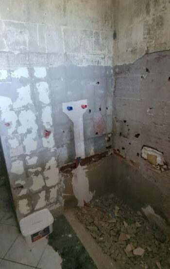 Début des travaux de rénovation avec mur dénudé et arrivées d’eau visibles