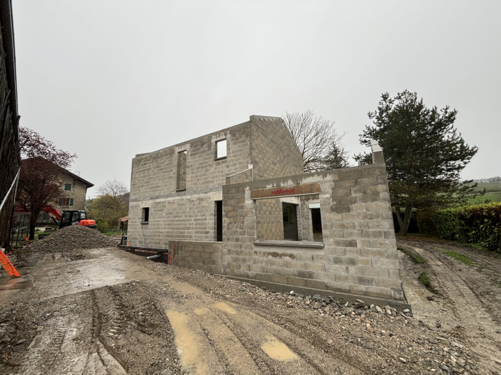 Construction des fondations en béton d'une maison à Douvaine par temps pluvieux.