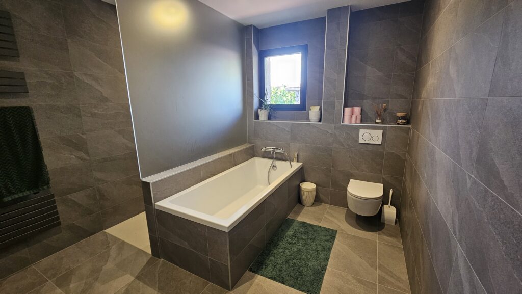 Salle de bains moderne avec baignoire encastrée et WC suspendu à Douvaine.