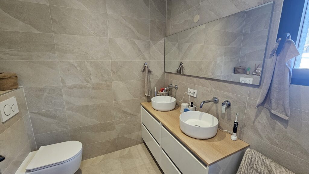 Espace salle d’eau avec douche à l’italienne et radiateur sèche-serviettes blanc à Douvaine.