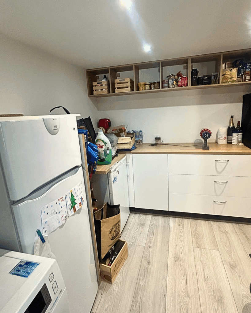 Buanderie fonctionnelle aménagée dans un garage rénové, avec rangements en hauteur, plan de travail et électroménagers intégrés.
