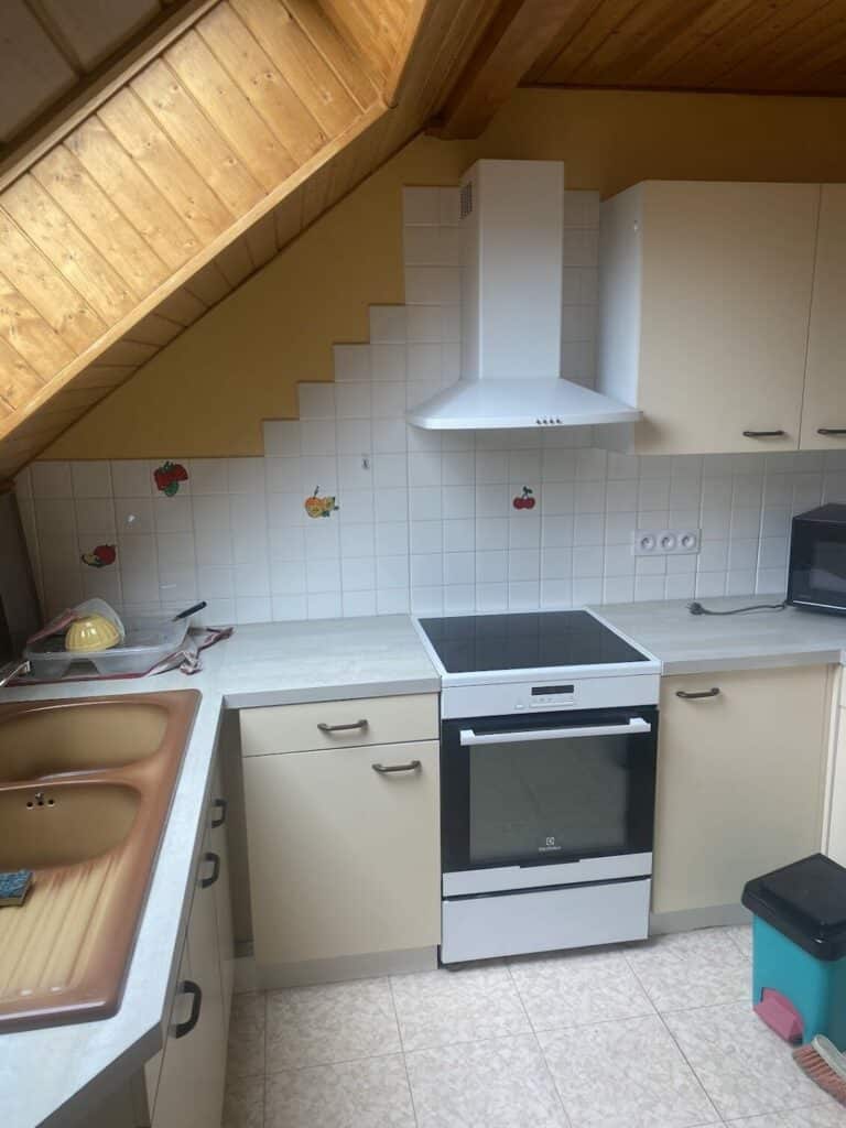 Ancienne cuisine sous combles avec mobilier beige et carrelage daté à Bons-en-Chablais.