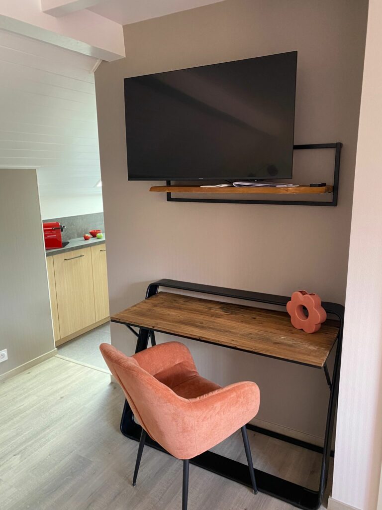 Coin bureau aménagé sous les combles avec bureau en bois et fauteuil en velours