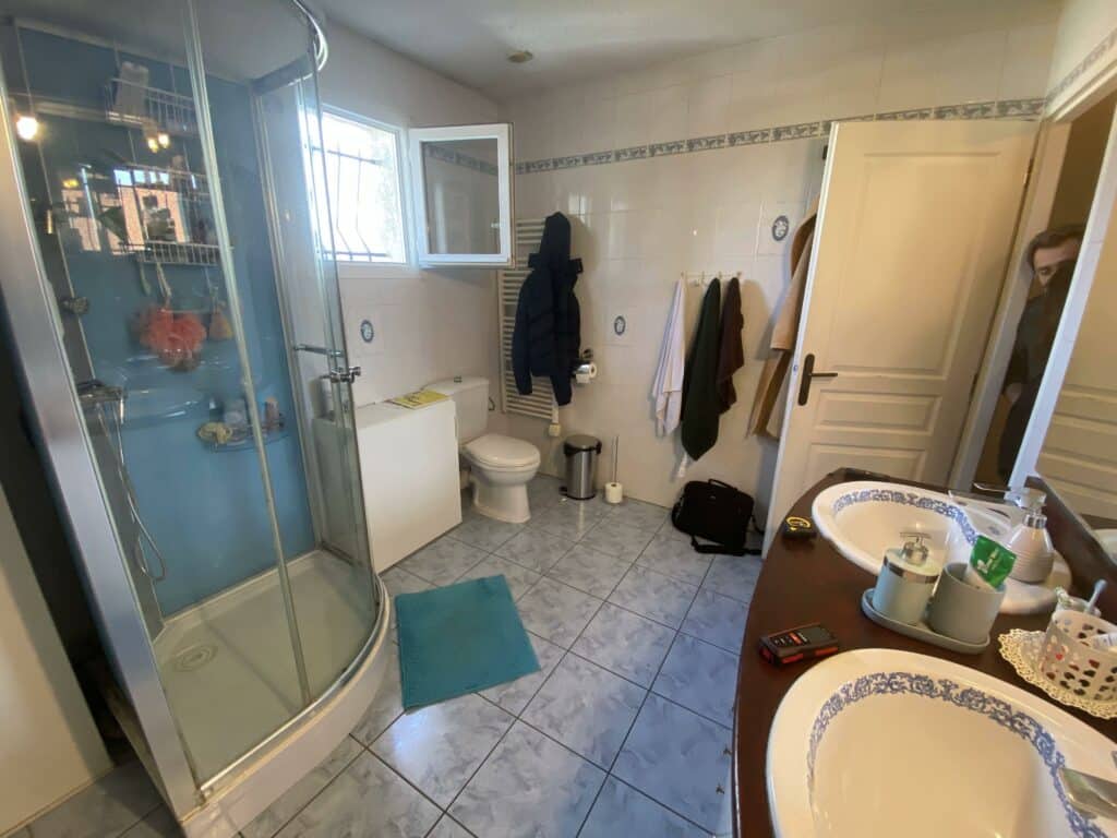 Salle de bains à Douvaine avant rénovation avec cabine de douche arrondie, WC et carrelage au sol classique.