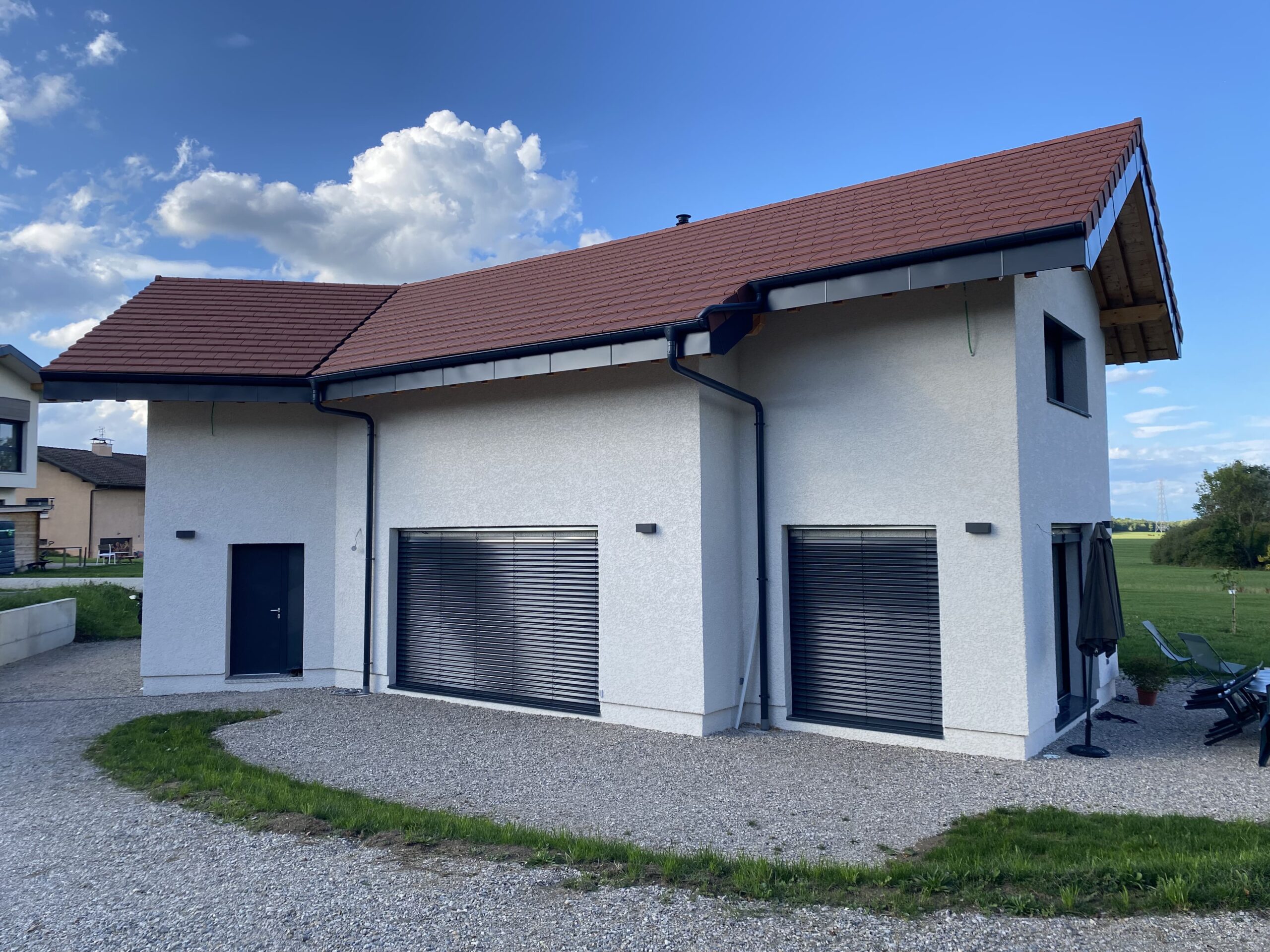 Maison moderne construite à Bons-en-Chablais par Le MieuxDisant avec façade crépie blanche et toiture en tuiles rouges.