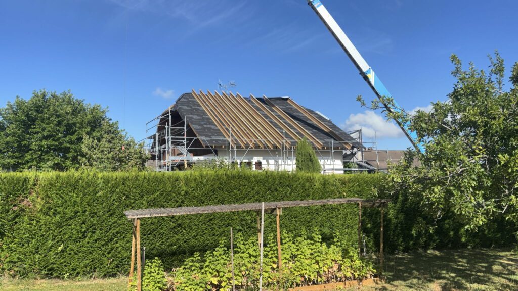 Chantier de rénovation de toiture à Bons-en-Chablais avec échafaudages et pose de charpente.