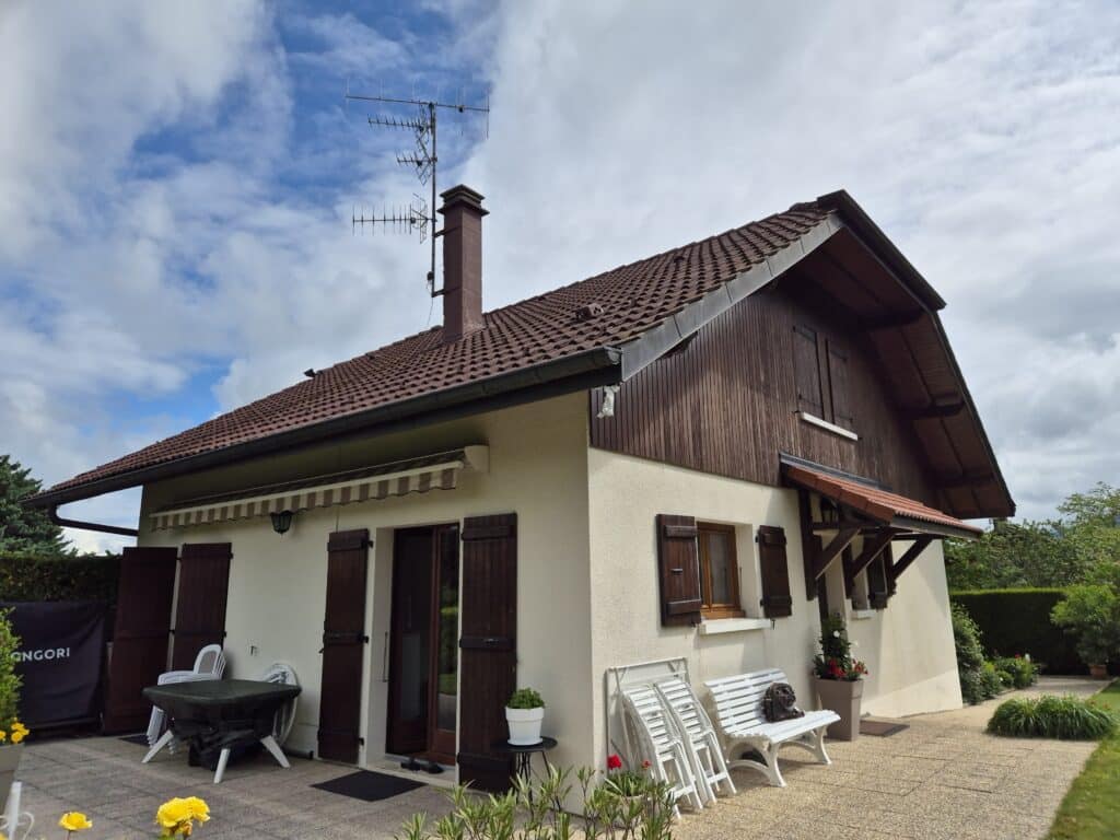 Maison rénovée à Bons-en-Chablais avec toiture refaite et charpente apparente en bois.