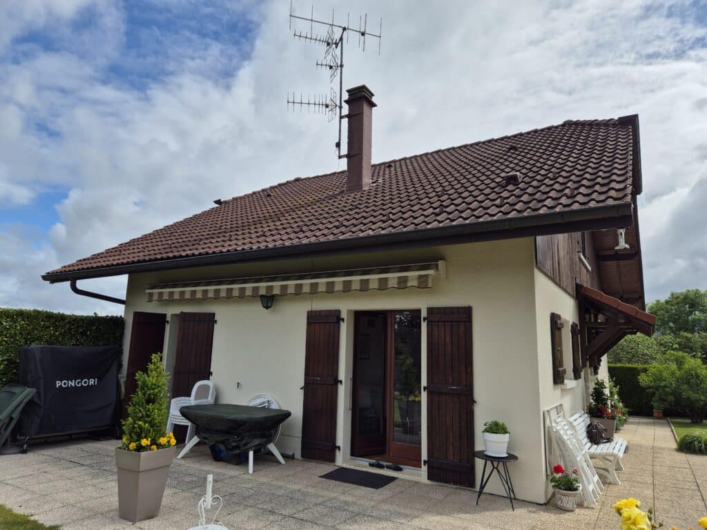 Rénovation de toiture à Bons-en-Chablais sur une maison de style chalet avec tuiles rouges et volets bois.