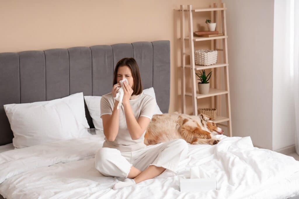 Femme allergique éternuant dans sa chambre à cause des poils d’animaux et des allergènes domestiques.
