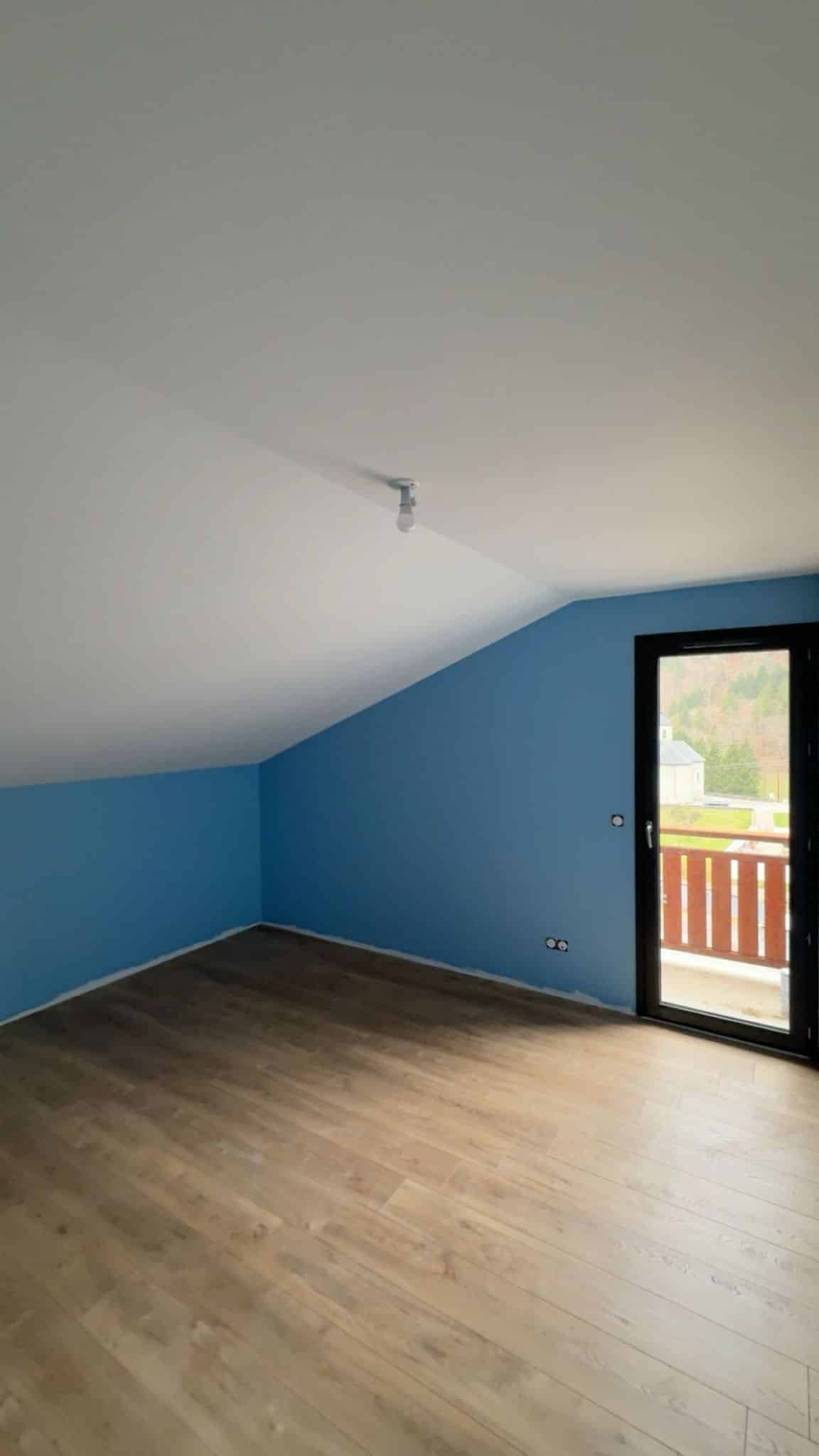 Chambre rénovée à Bons-en-Chablais avec peinture bleue et sol parquet