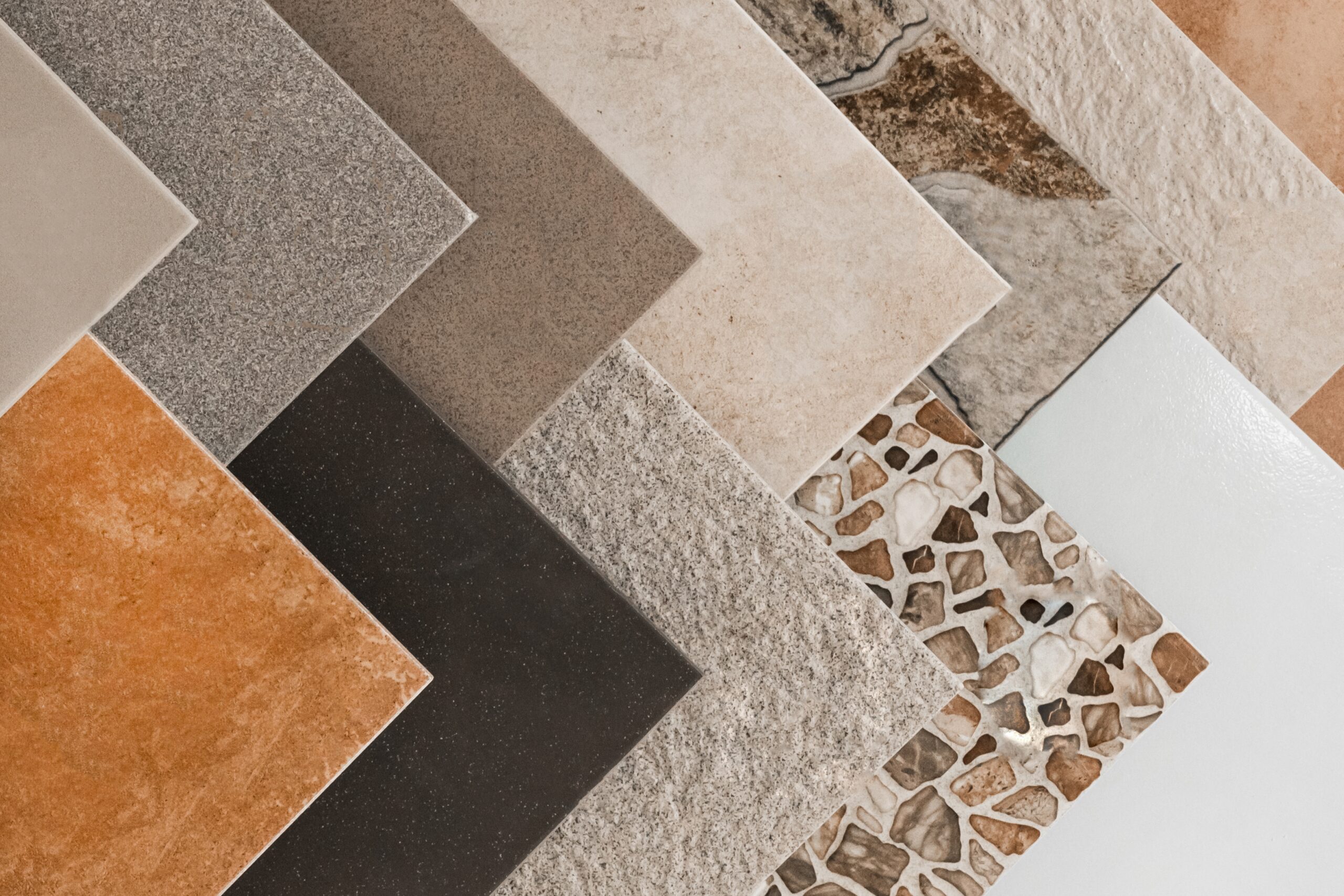 Échantillons de carrelage tendances disposés en éventail : grès cérame, pierre naturelle, mosaïque et faïence unie
